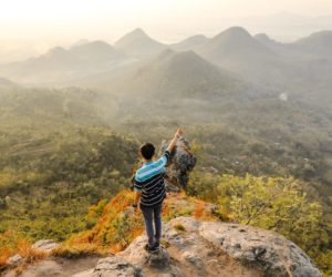 photo of man standing on rock mountain pointing out mountain 842687